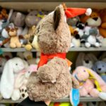 Плюшева іграшка оленя в червоній шапці