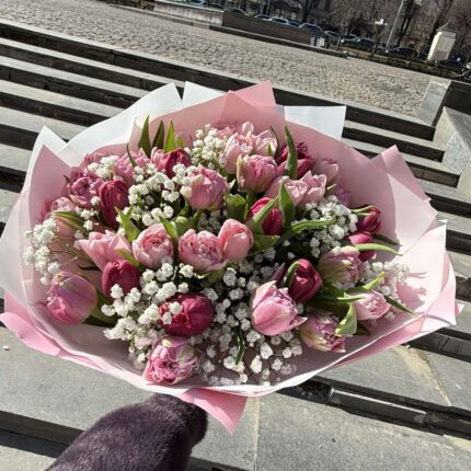 Букет весняних квітів на фоні міського пейзажу.