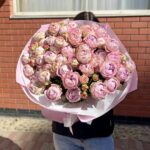 Великий букет рожевих півоній у руках.