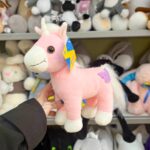 Рожева іграшкова єдиноріжка на фоні інших м’яких іграшок