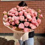 Великий букет рожевих троянд на фоні стіни.